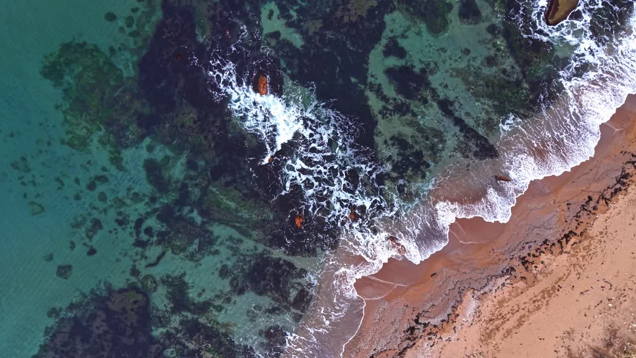 View of shoreline with waves breaking on rocky coast during midday