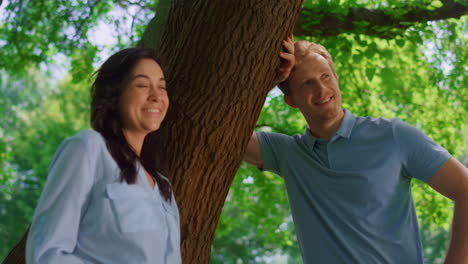 smiling pair standing on nature closeup . happy couple relax lean on tree trunk.