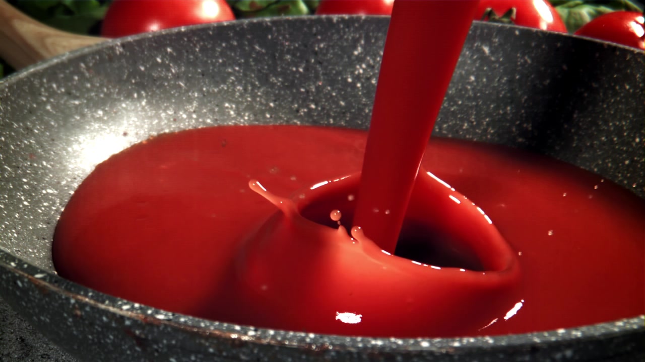 Versamento al rallentatore di salsa di pomodoro rossa in una padella.