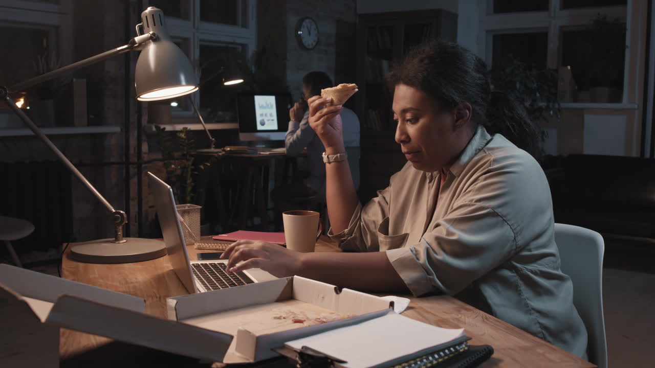 Woman Working Late in Office Eating Pizza and Drinking Coffee