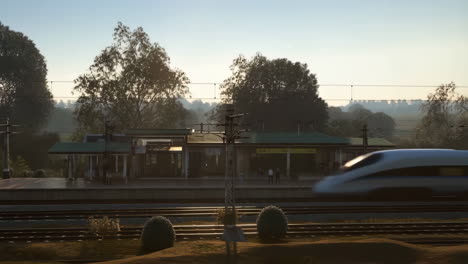 a high-speed train passes by a station on a sunny day