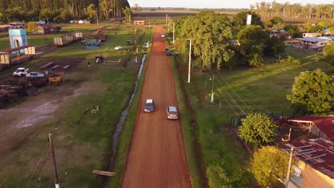 Aerial-view-of-cars-driving-down-a-dirt-road