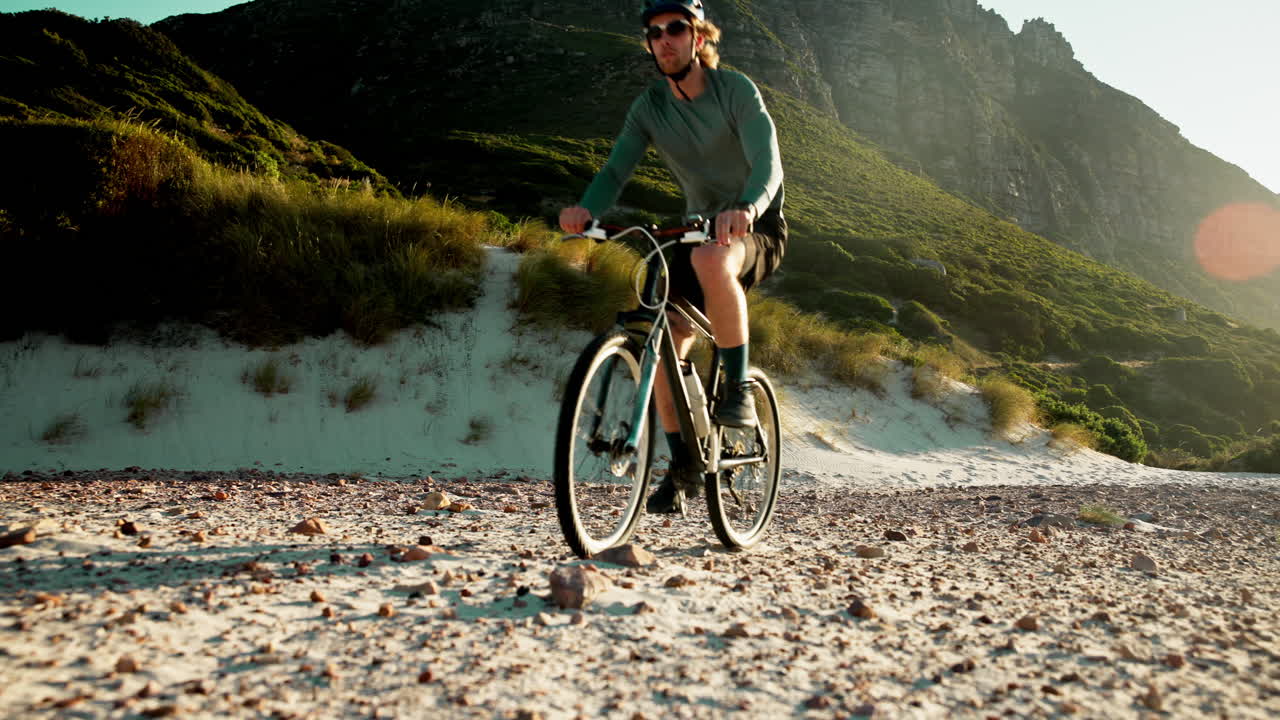 Uomo avventuroso in mountain bike su un sentiero sabbioso e roccioso.
