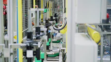 brazo de robot amarillo de alta precisión pega pegatinas en los productos finales - amortiguadores de automóviles en la línea de producción
