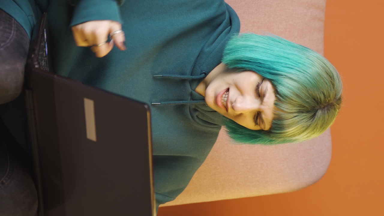 노트북에서 본 것에 화를 내는 젊은 여성의 수직 비디오입니다.