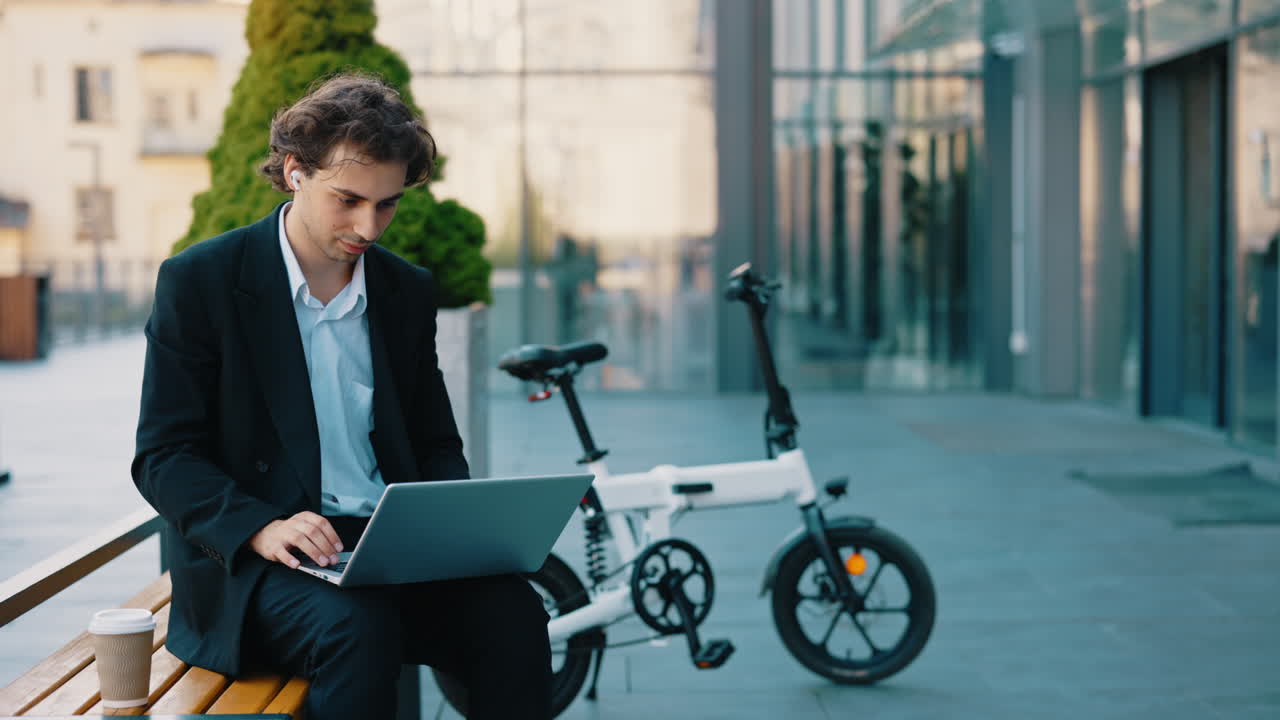 Businessman working outdoors with a laptop and e-bike