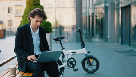 businessman working outdoors with a laptop and e-bike