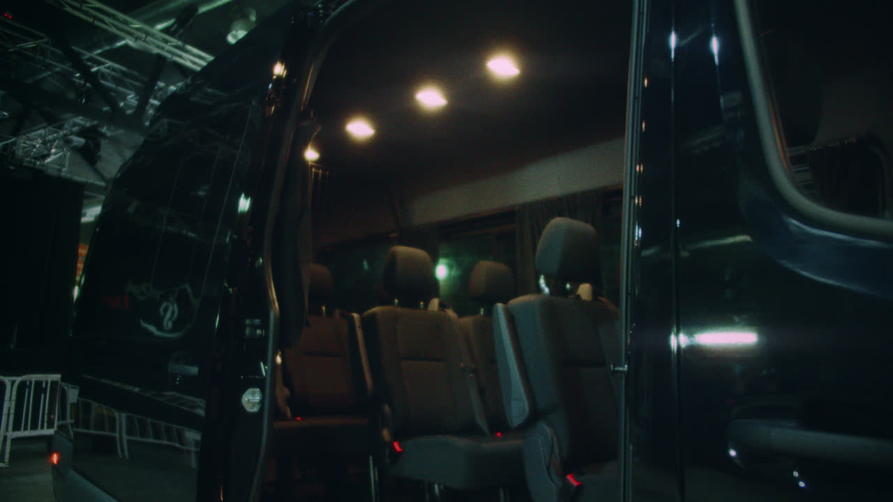Beautiful slow motion, 4k shot of a van with the door open with its wide, clean seats. Parked in a large dark warehouse.