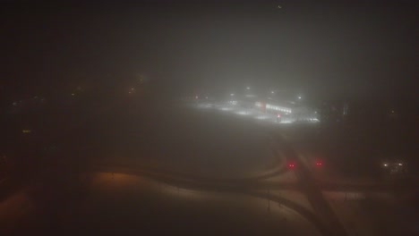 snowy landscape at night with fog and city lights and empty freeway