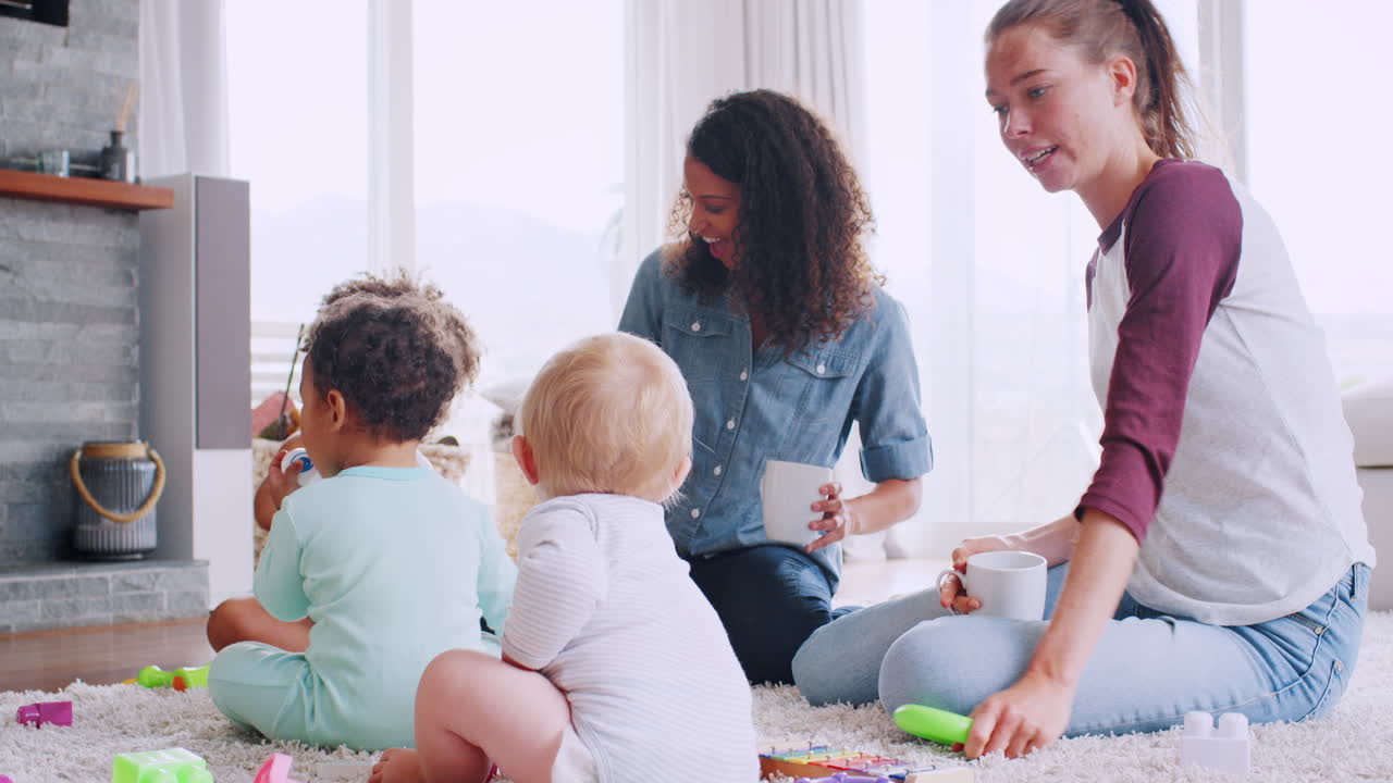 dos mujeres jugando con sus niños en el suelo