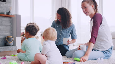 Dos-Mujeres-Jugando-Con-Sus-Niños-Pequeños-En-El-Suelo