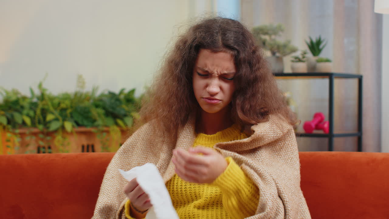 больной ребенок девушка страдает от простуды или аллергии сидит на домашнем диване чихает вытирает морду в салфетку