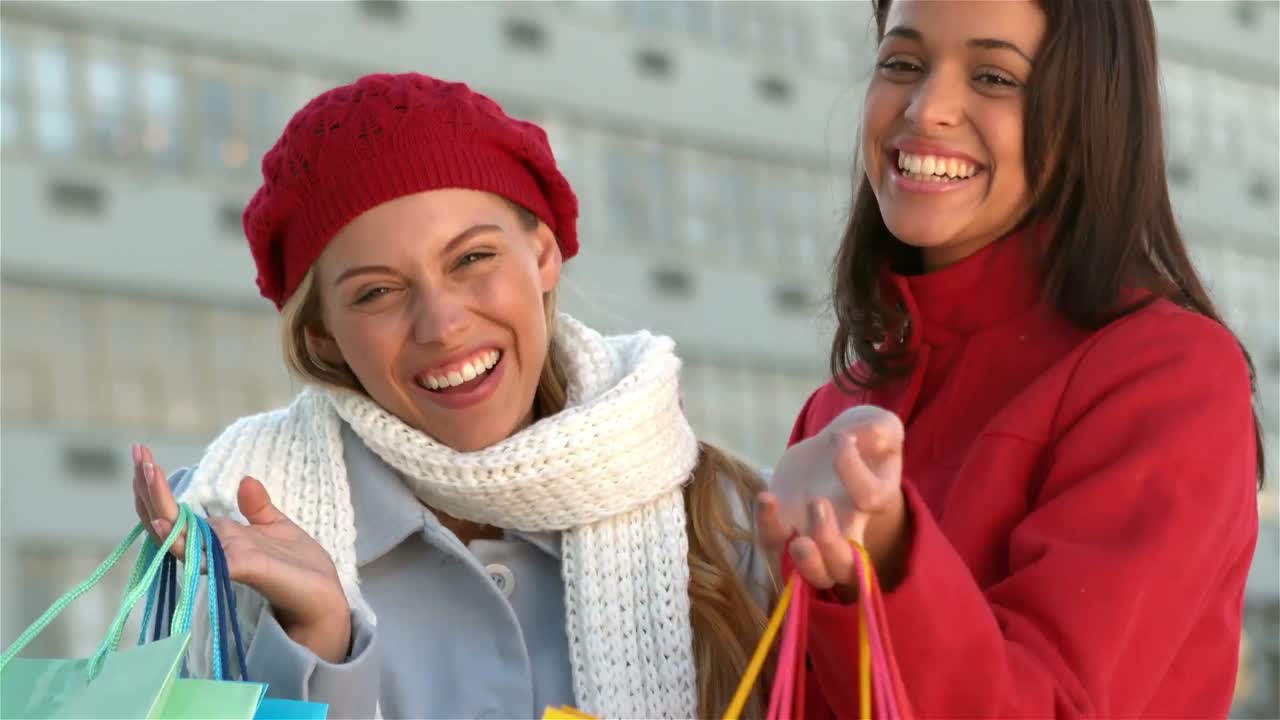 chicas sonrientes que muestran bolsas de compras bonitas