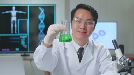 young asian male research scientist looking  glass test tube and warmly smiles into the camera