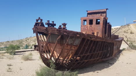 Barco-Oxidado-Abandonado-En-La-Arena-Del-Antiguo-Lago-Aral,-Restos-Corroídos-Del-Barco-En-Un-Día-Caluroso-Y-Soleado