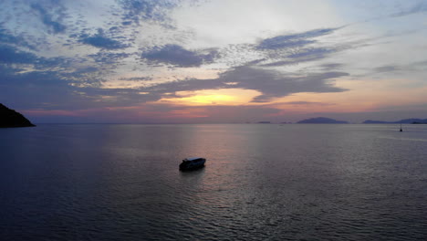 imágenes de drones de barcos anclados en un océano pacífico con una colorida puesta de sol en el fondo