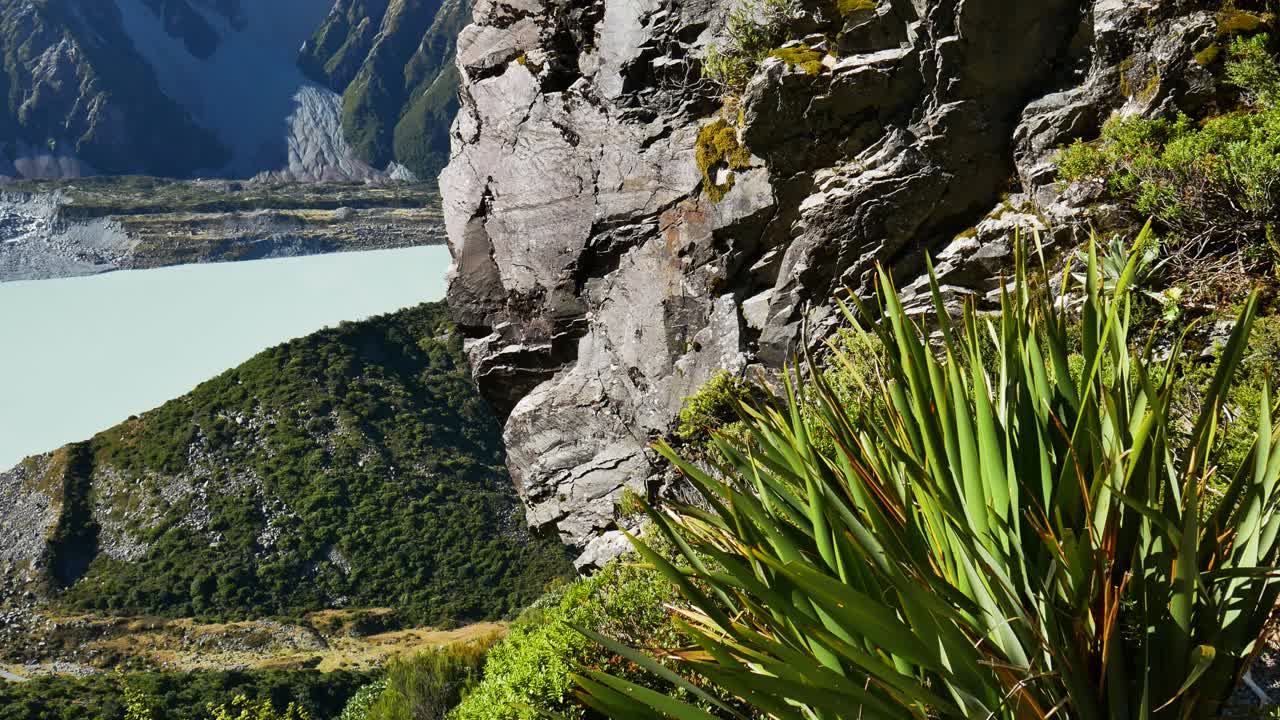 rocky cliff face with lake and mountains in background