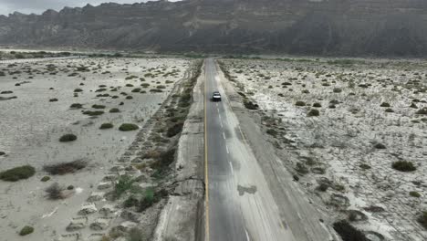 Verfolgung-Von-Drohnenaufnahmen-Eines-Jeep-Autos-Von-Vorne-Auf-Einer-Geraden-Straße-Zwischen-Tal-Und-Berg-Hingol-Belutschistan