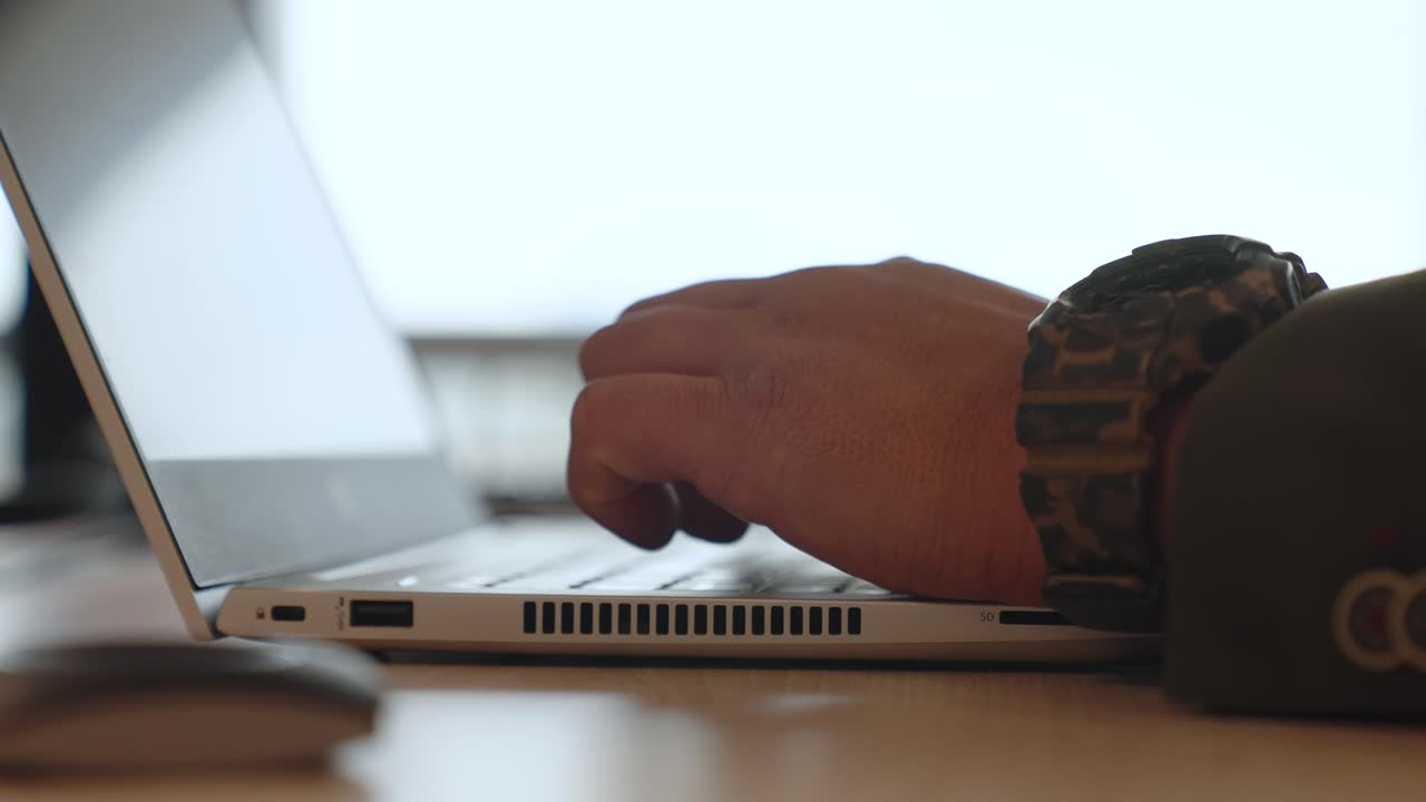 Detailed shot of fingers typing on a laptop, zoom-in movement capturing digital workflow