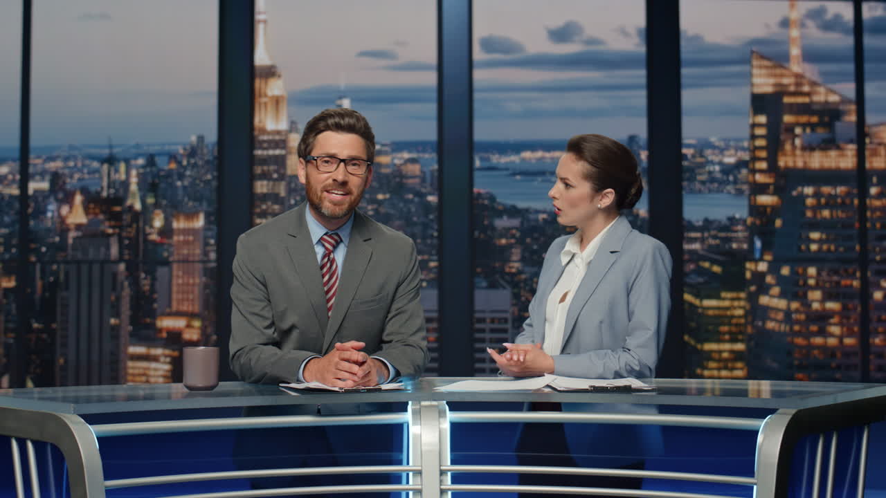 pareja de presentadores discutiendo noticias de pie canal de televisión nocturno estudio de primer plano