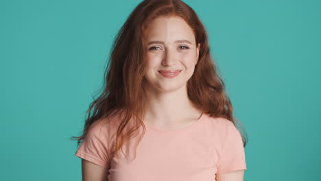 redheaded girl looking at camera on turquoise background.