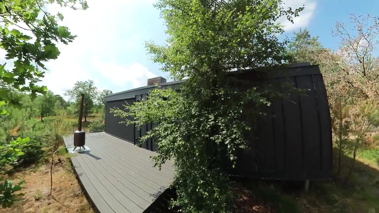 Et roligt og moderne tilflugtssted med elegante sorte hytter integreret i en frodig skov. Højdepunkter inkluderer fredfyldte naturomgivelser, hytternes moderne design, arkitektur og natur.