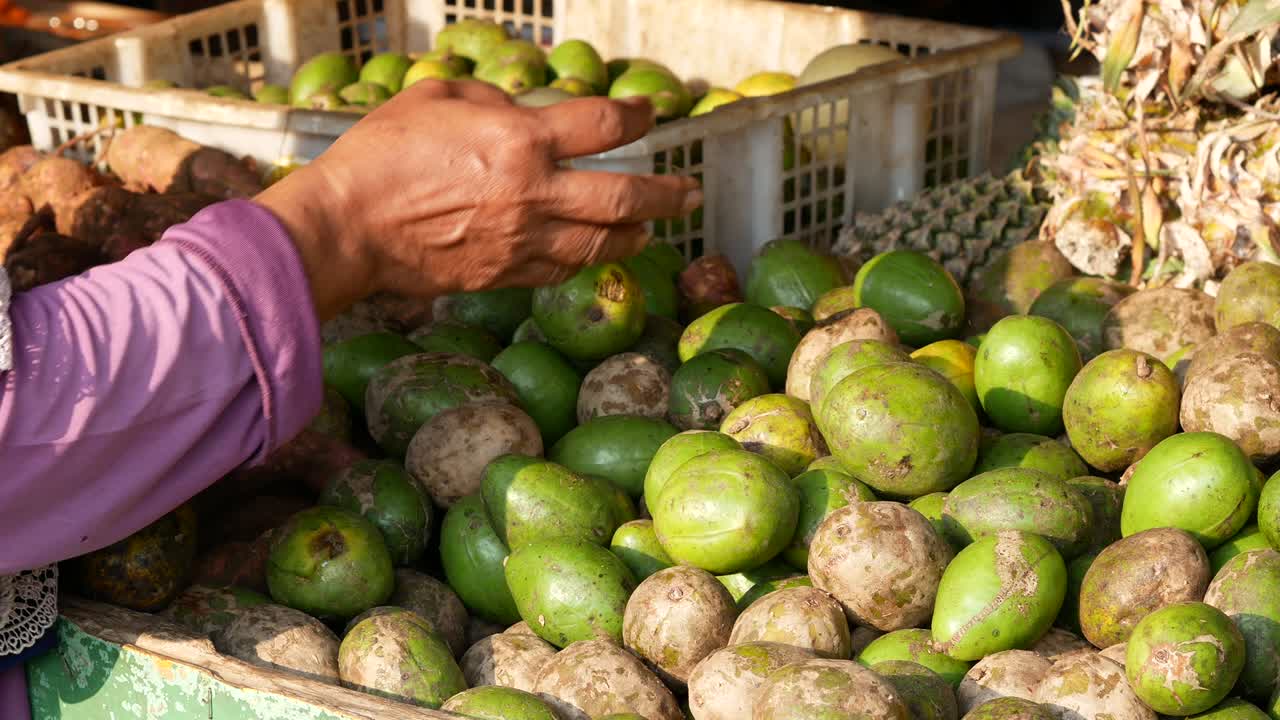 una mujer indonesia está eligiendo frutas en un mercado húmedo tradicional.