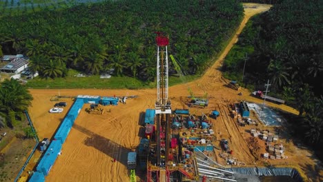 Cinematic-Onshore-Drilling-and-Workover-Rig-structure-and-Rig-equipment-for-oil-exploration-and-exploitation-in-the-middle-of-jungle-surrounded-by-palm-oil-trees-during-sunset-time