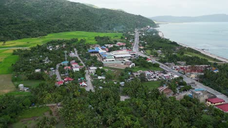 Virac-downtown,-catanduanes-with-lush-greenery-and-coastal-road,-aerial-view