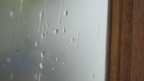cámara lenta de agua en una ventana mientras llueve al fondo