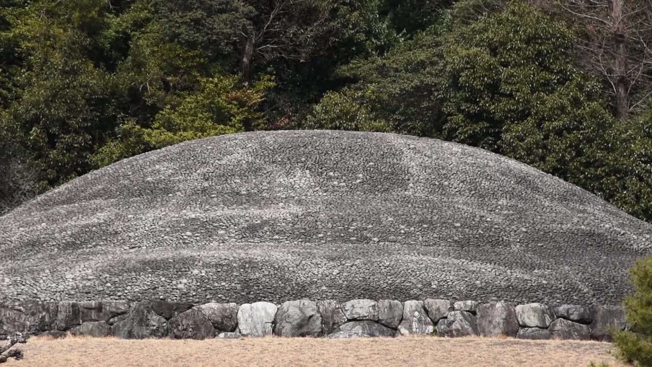 Close up view of Emperor Kōmei’s mausoleum in Kyoto, surrounded by trees and grassy mounds.