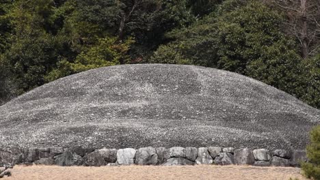close up view of emperor kōmei’s mausoleum in kyoto, surrounded by trees and grassy mounds.
