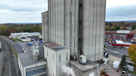 industrial silos with steam venting next to railroad tracks