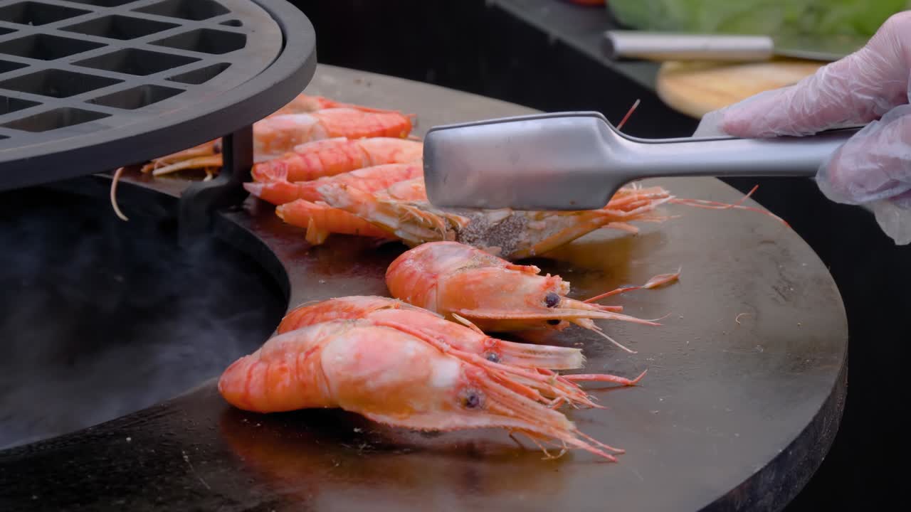 Slow motion: chef grilling fresh red king prawns on brazier - close up view