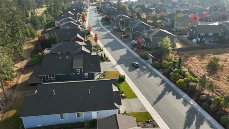 aerial shot tracking a car driving through a suburban neighborhood nearing sunset