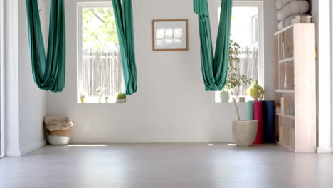 Empty-white-room-with-hanging-gymnastic-sashes-over-plants-and-wardrobe,-slow-motion