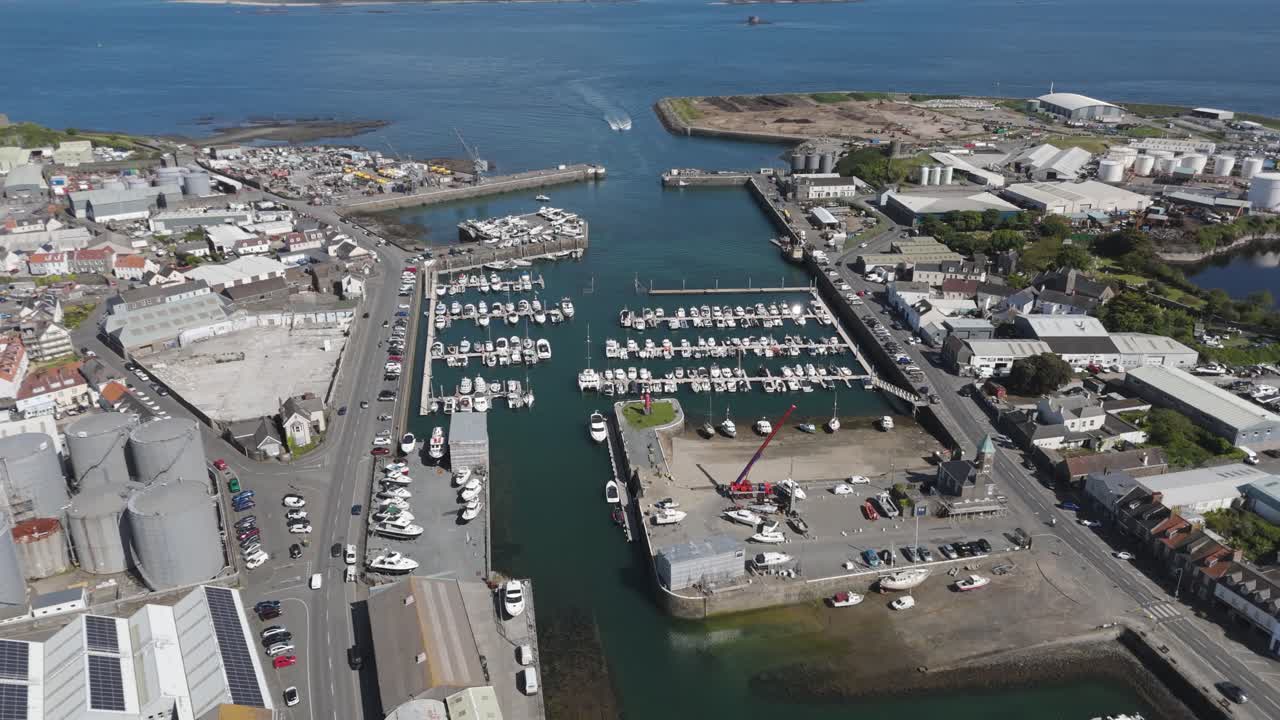 High reveal drone footage of St Sampson’s Harbour Guernsey showing docks,marina and surrounding commercial area on bright sunny day