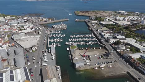 high reveal drone footage of st sampson’s harbour guernsey showing docks,marina and surrounding commercial area on bright sunny day