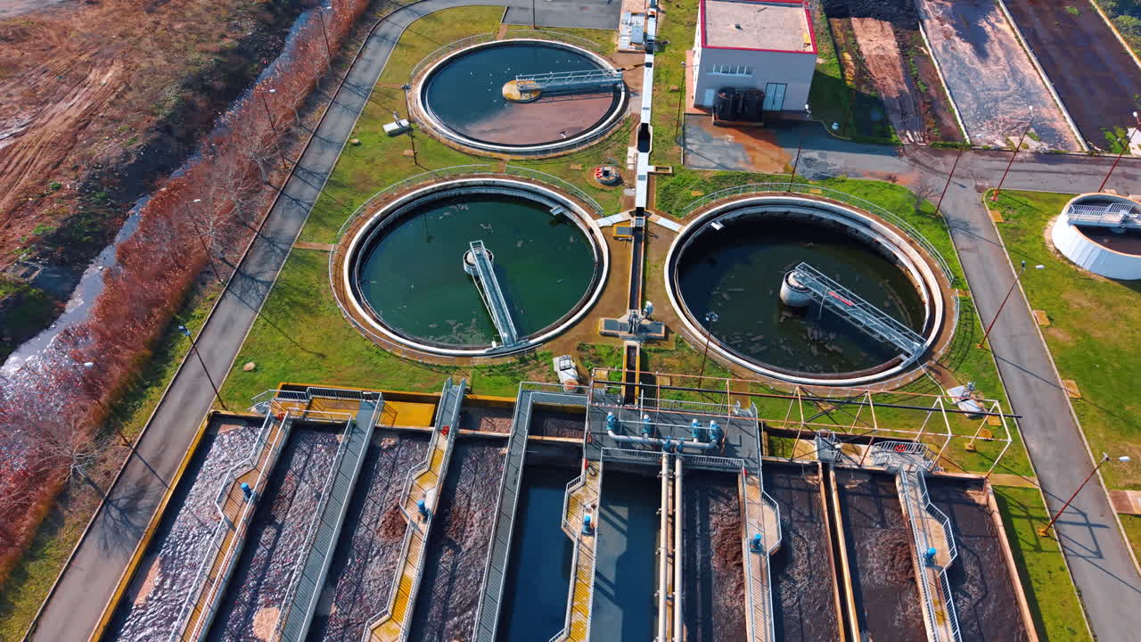 Aerial view of circular sedimentation tanks at wastewater treatment plant. High angle shot of three round water purification basins with rotating bridges in industrial facility