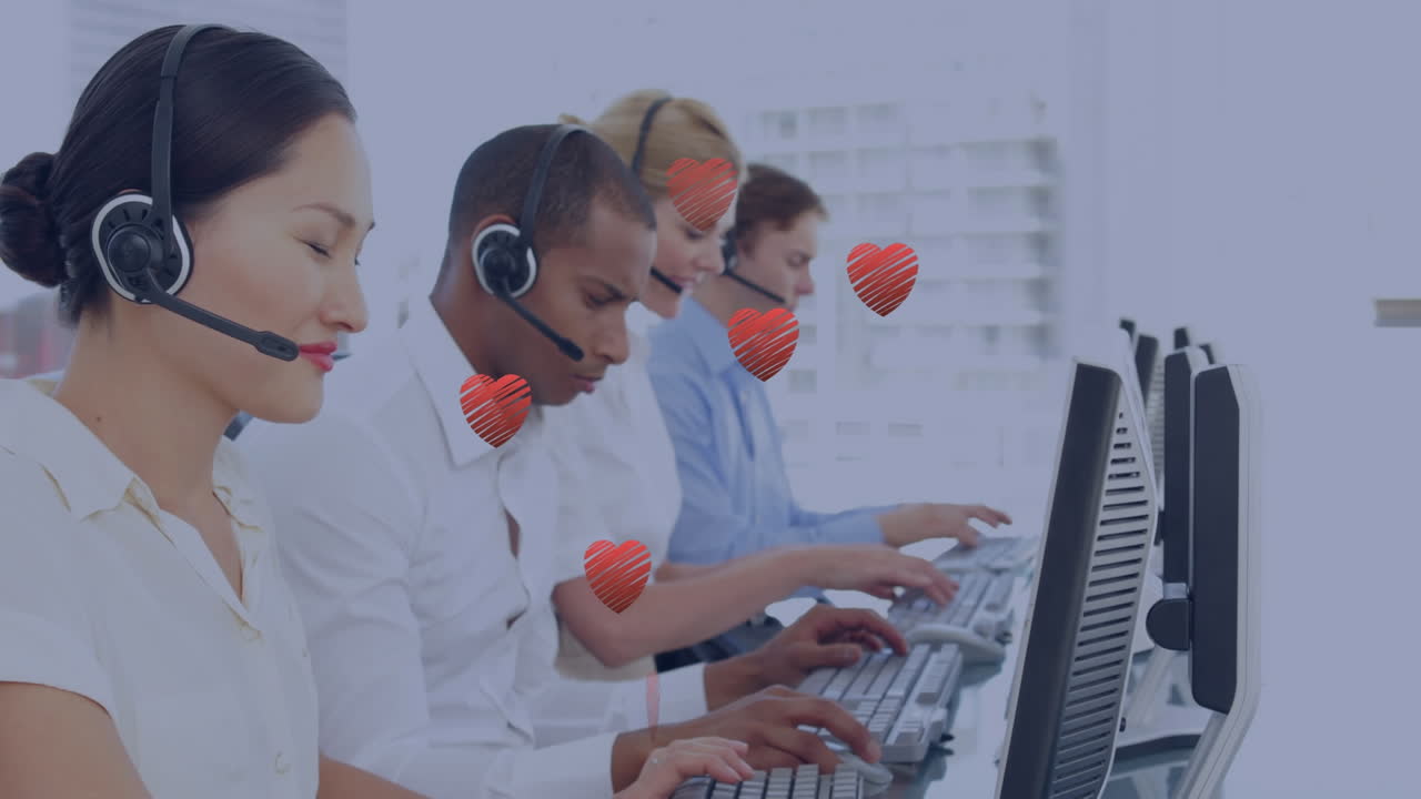 Multiple red heart icons floating against team of diverse customer care executives working at office