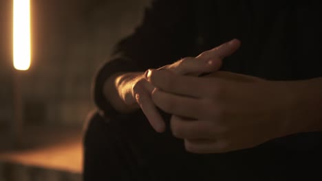 close shot of stressed man waiting soemthing sitting on stairs turning his ring in his finger