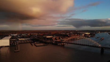 dramatic clouds in sunset over arch bridge spanning noord river in alblasserdam, netherlands