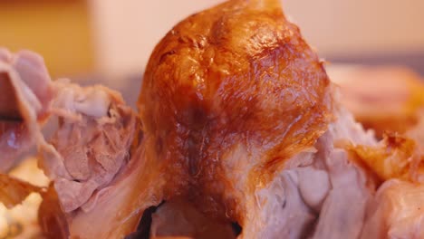 rotating shot around roasted turkey joint as meat is carved and plated at christmas or thanksgiving dinner table for family celebration in holidays season 4k.