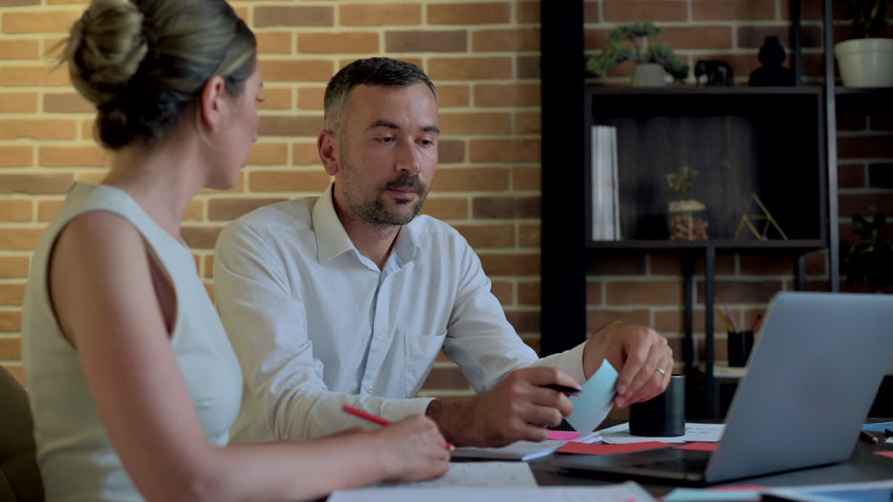 Un uomo e una donna parlano e indicano un computer su una scrivania in un ufficio
