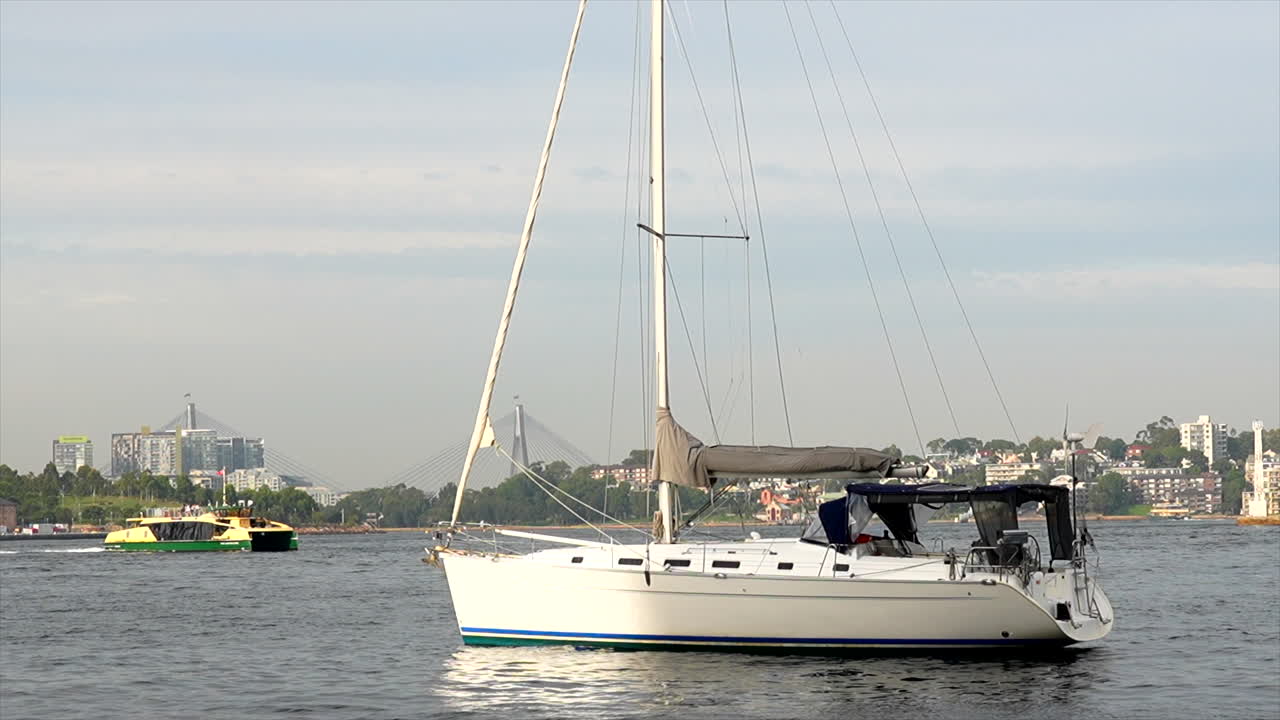 Un traghetto passa dietro uno yacht privato nel porto di Sydney, Australia.