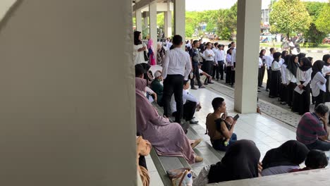 large group of people in uniform waiting in line outdoors