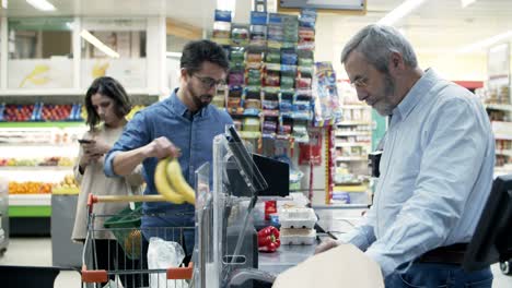 cashier and buyers at pay desk in supermarket