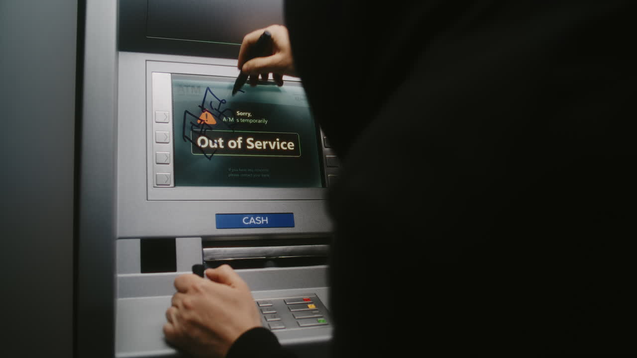Unrecognizable Vandal in Hoodie Marking ATM Screen with Graffiti Using Marker Pen. Person Damaging Property, Vandalizing Out of Service Cash Machine with Illegal Graffiti. Vandalism in Public Place.