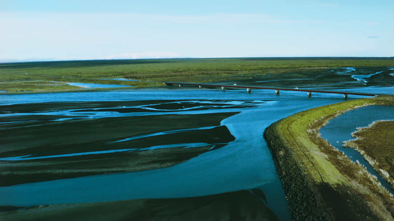 Aerial : Aerial view of a volcanic river and traffic over bridge. Aerial Views of Iceland's Volcanic Rivers. Icelandic Glacial Braided River. Stunning shot of Icelandic river delta seen from above.