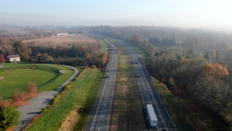 Toma-Aérea-De-Un-Carro-Sobre-Una-Autopista-Dividida-De-Dos-Carriles-En-Los-Estados-Unidos-De-América,-Ee.uu.-Durante-Un-Brillante-Día-De-Otoño-Brumoso